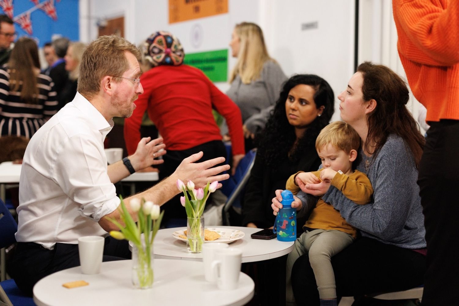John speaking with a young family at a community event