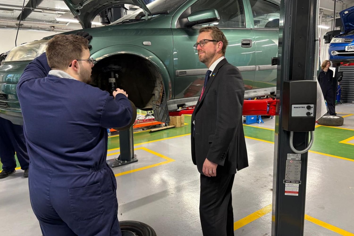 John at a local college, watching an apprentice work on a car